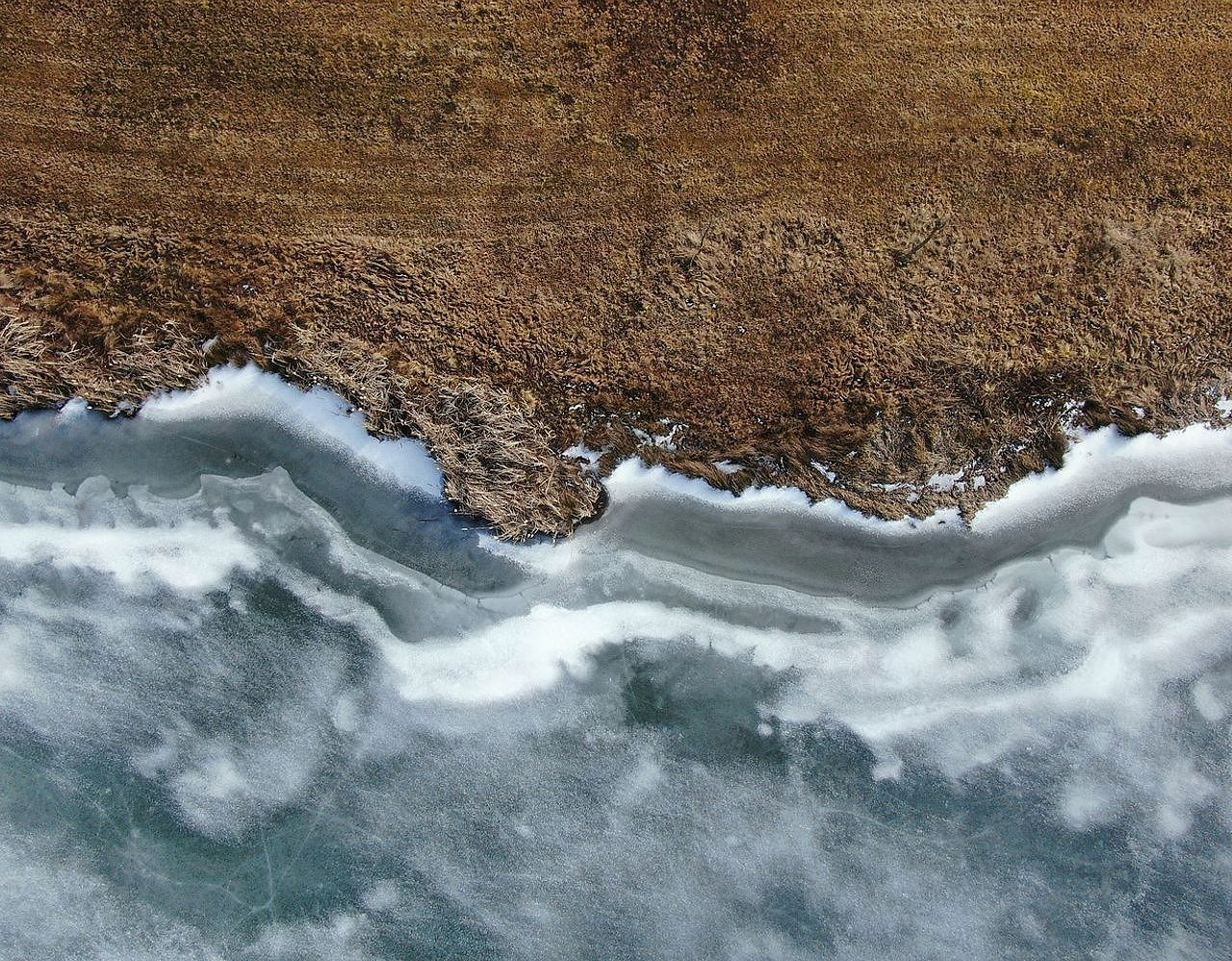 Un guía verificando el espesor del hielo con herramientas junto a una ventana